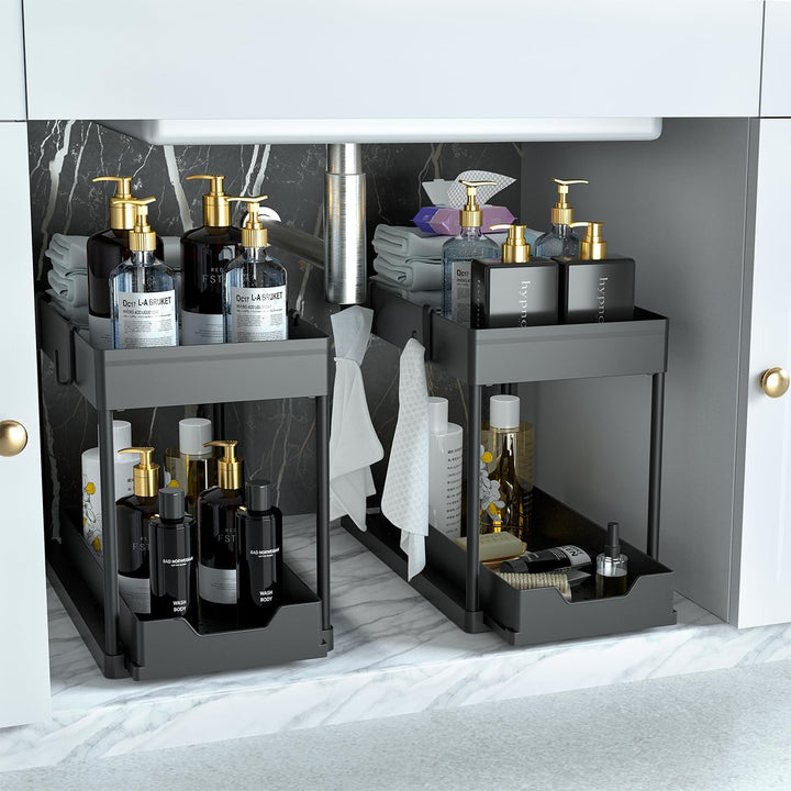 DEKAVA 2-pack black under sink organizers featuring a 2-tier design with sliding storage drawers, shown holding bathroom toiletries and cleaning supplies inside a marble-lined cabinet.